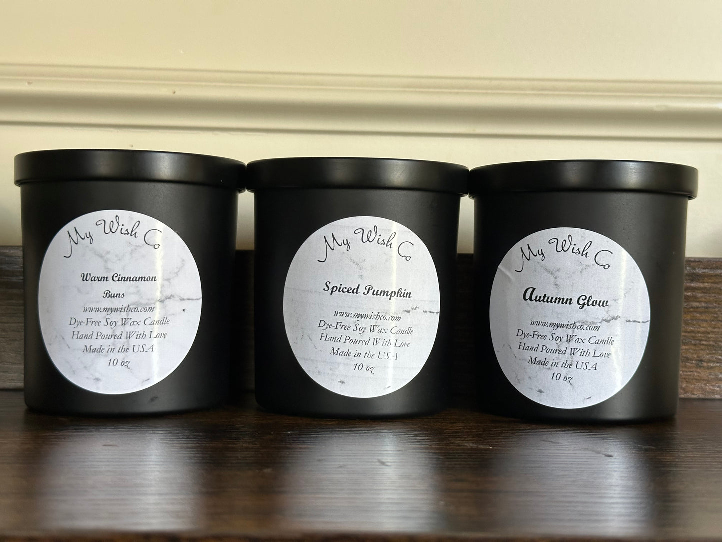 Three black candles with labels on a wooden surface