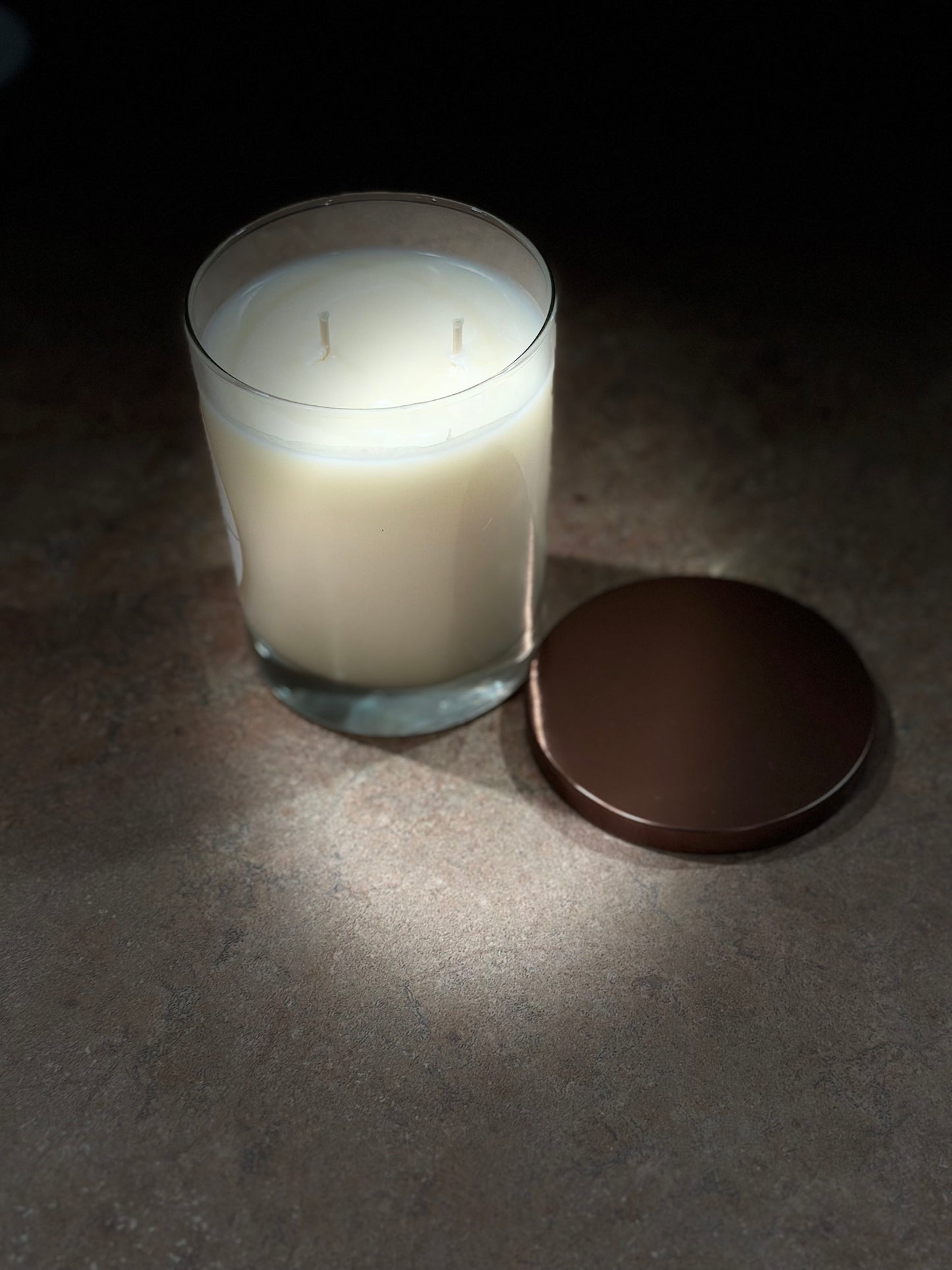 White candle in a glass jar with a brown lid 