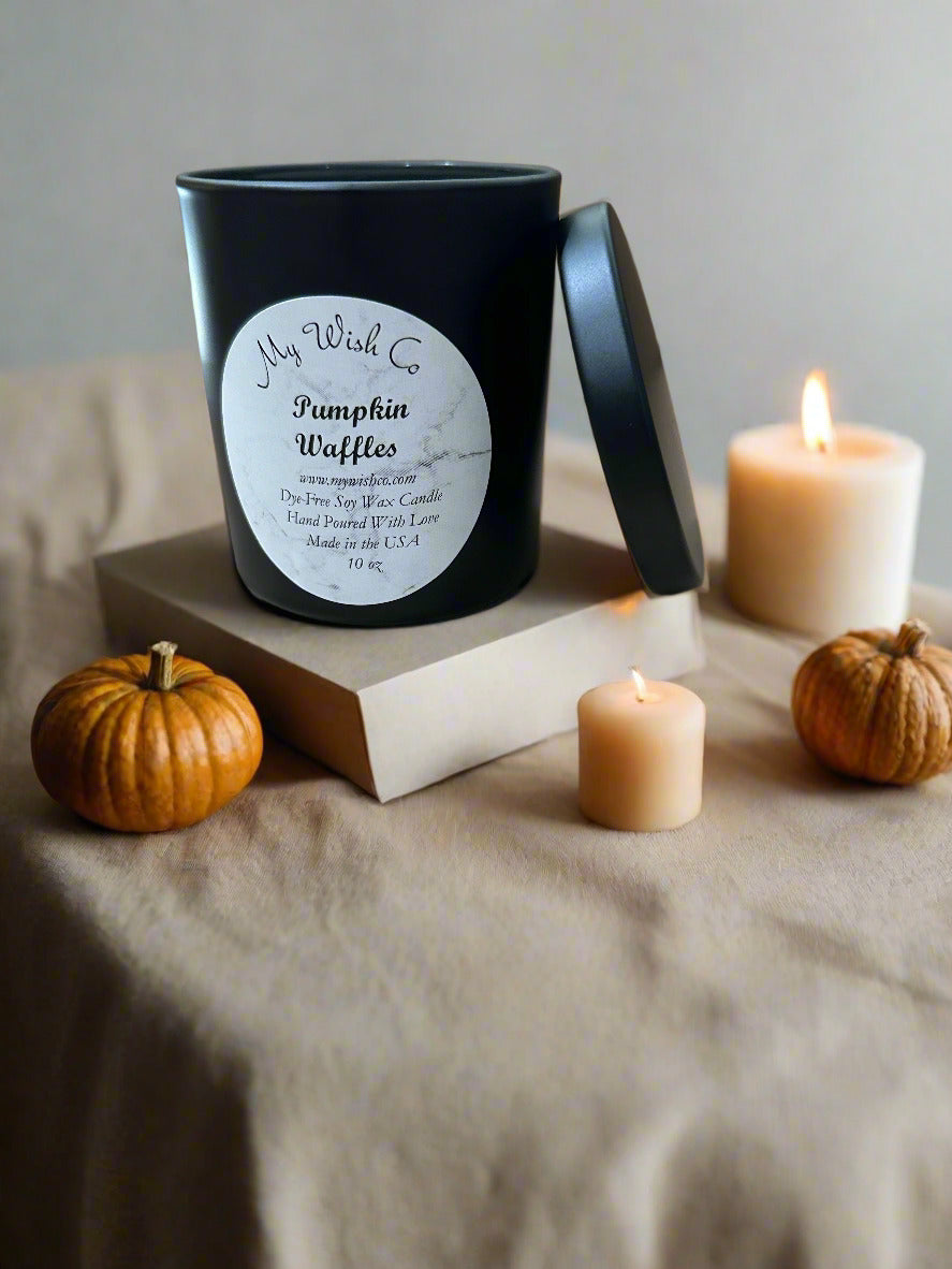 Candle labeled 'Pumpkin Waffles' with pumpkins and a lit candle on a neutral background