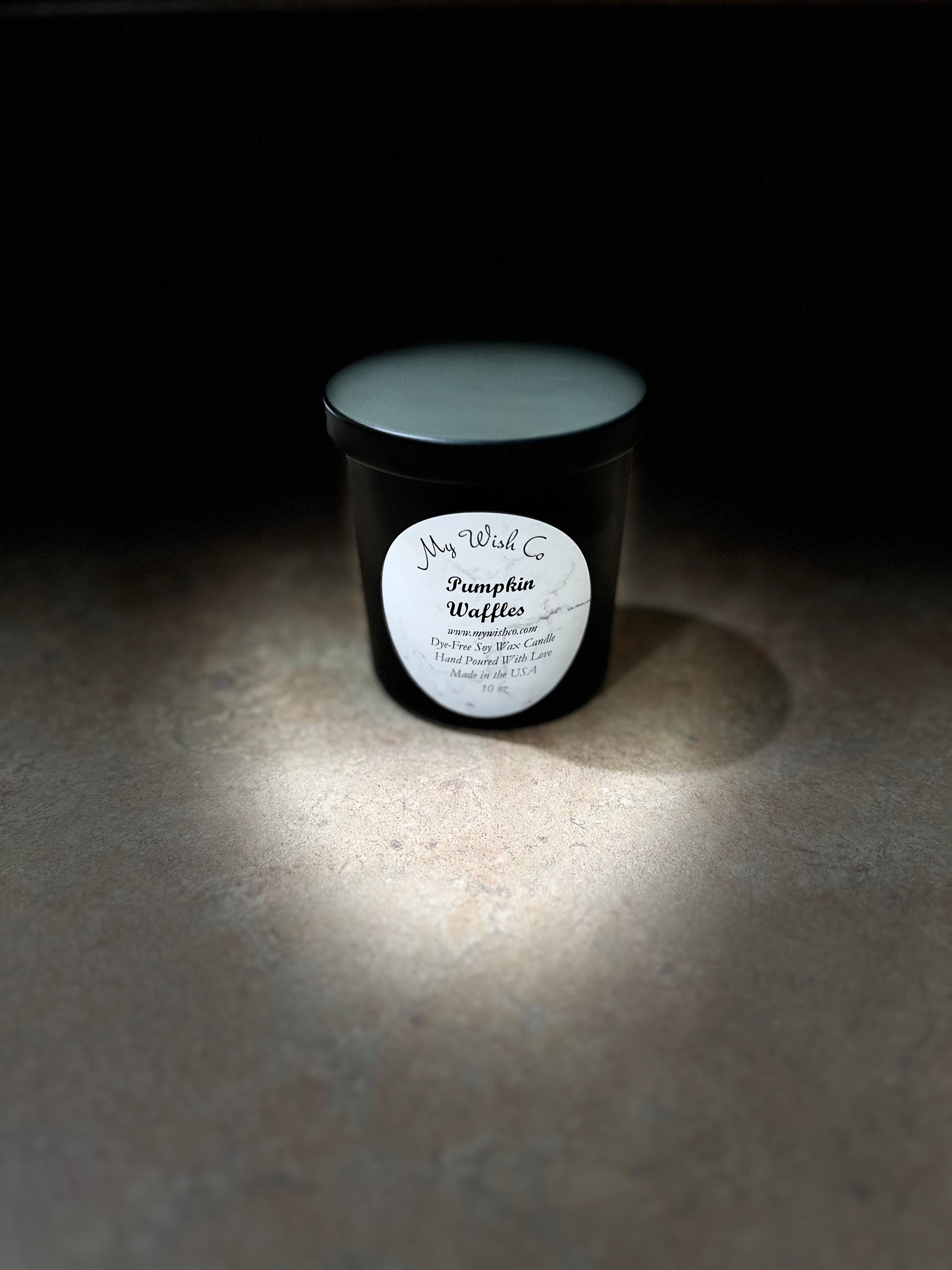 Candle in a black container with a white label on a dark background