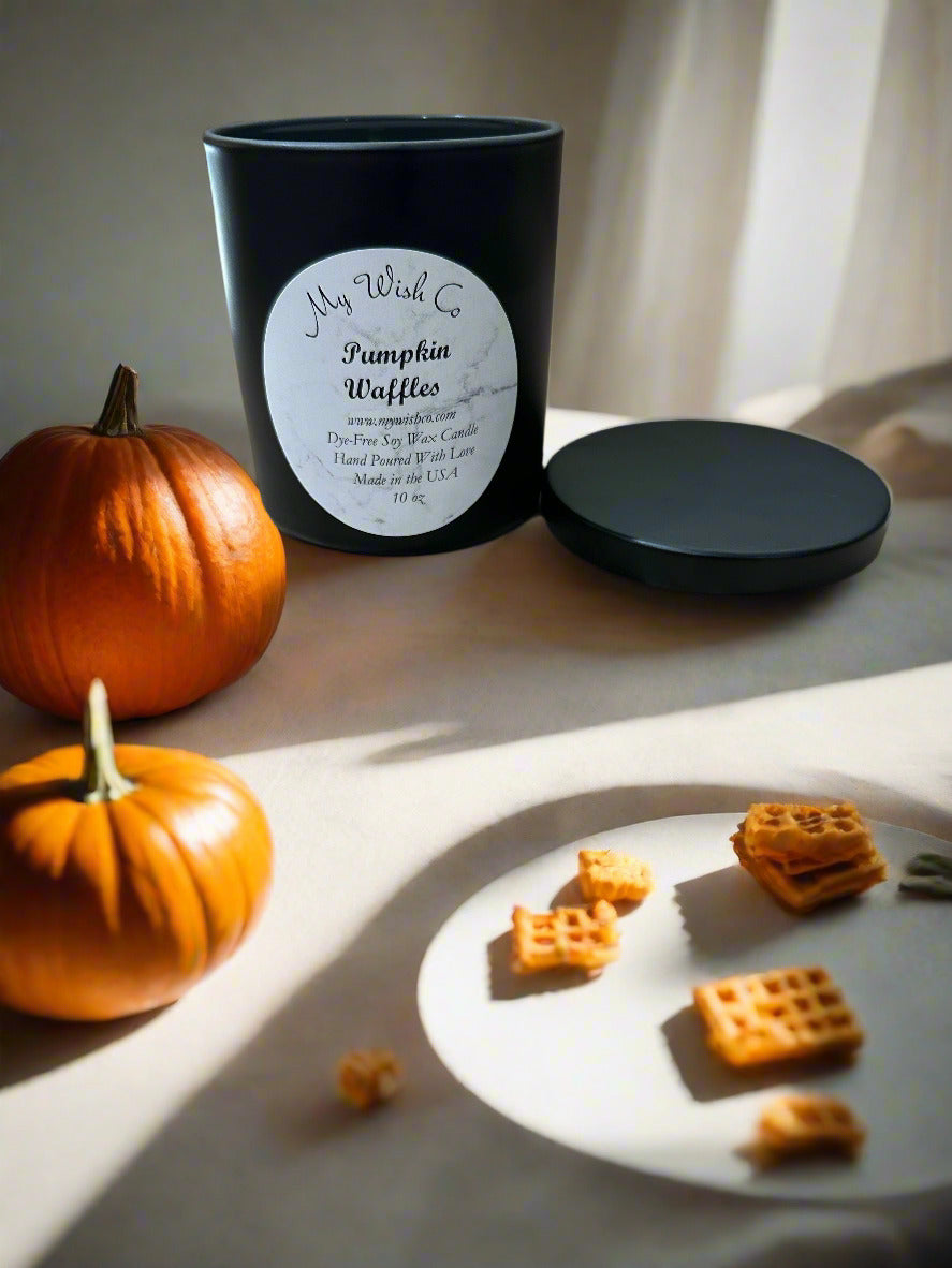 Candle labeled 'Pumpkin Waffles' with pumpkins and waffle cookies on a light surface