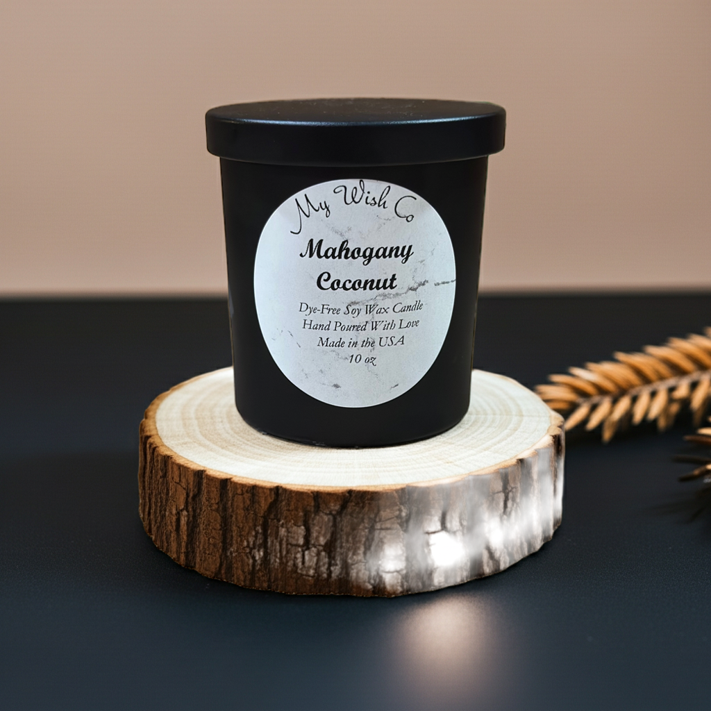 Black candle with a label on a wooden coaster against a dark background