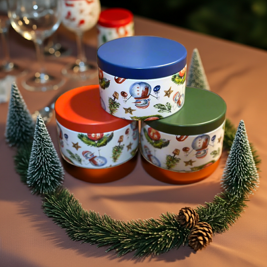 Decorative cylindrical containers with colorful lids on a table with Christmas-themed elements.