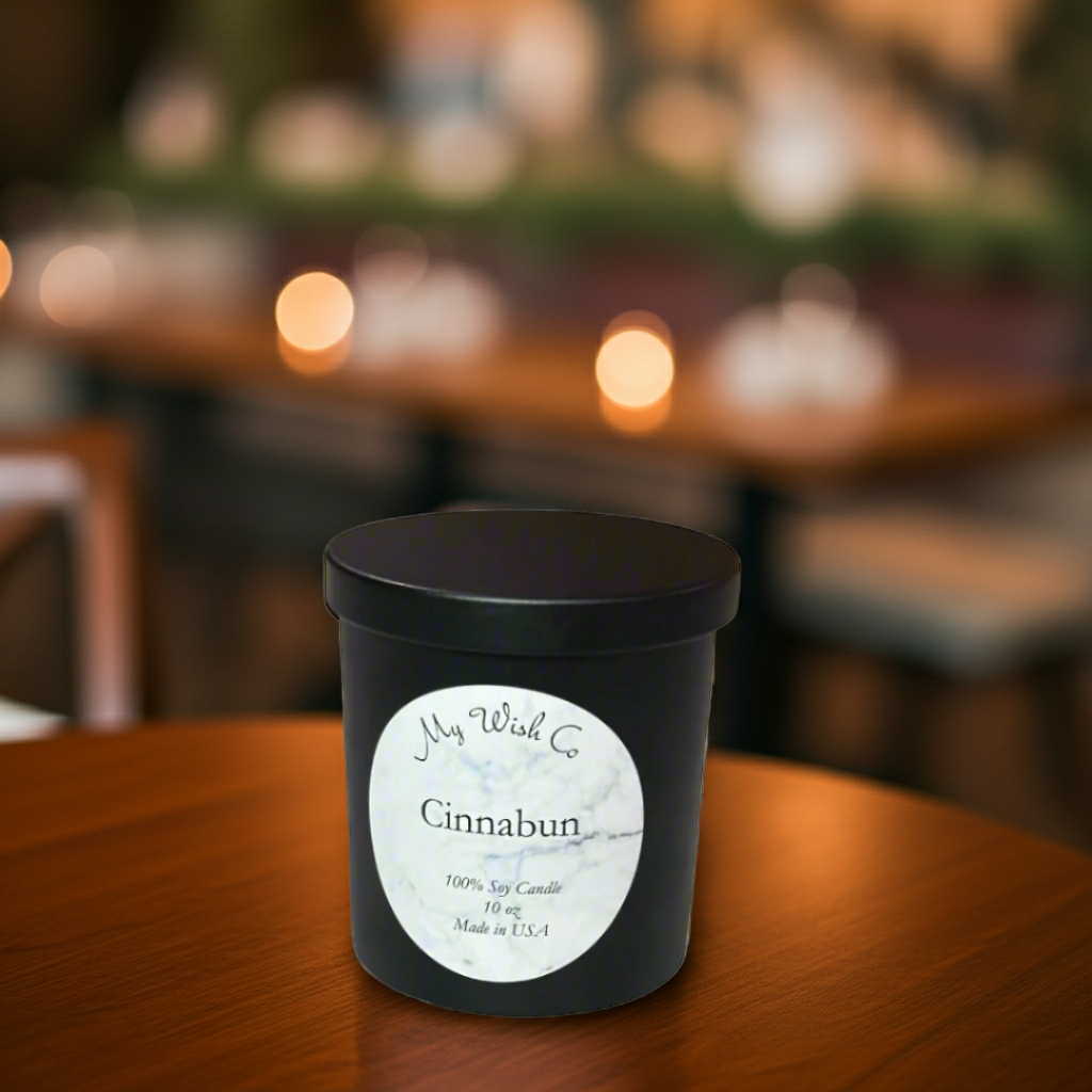 Black candle with a label on a wooden table in a softly blurred restaurant setting