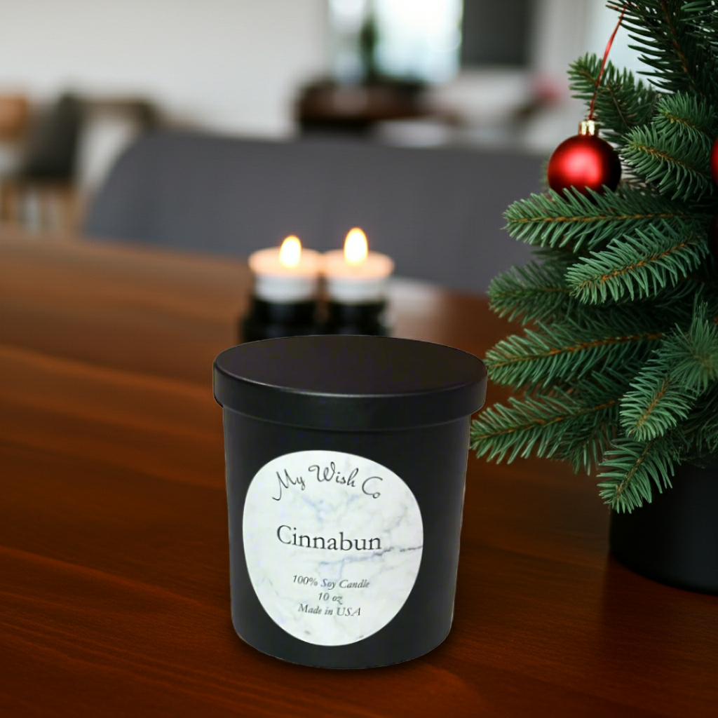 Black candle jar with 'My Wish Co' label on a table next to a Christmas tree