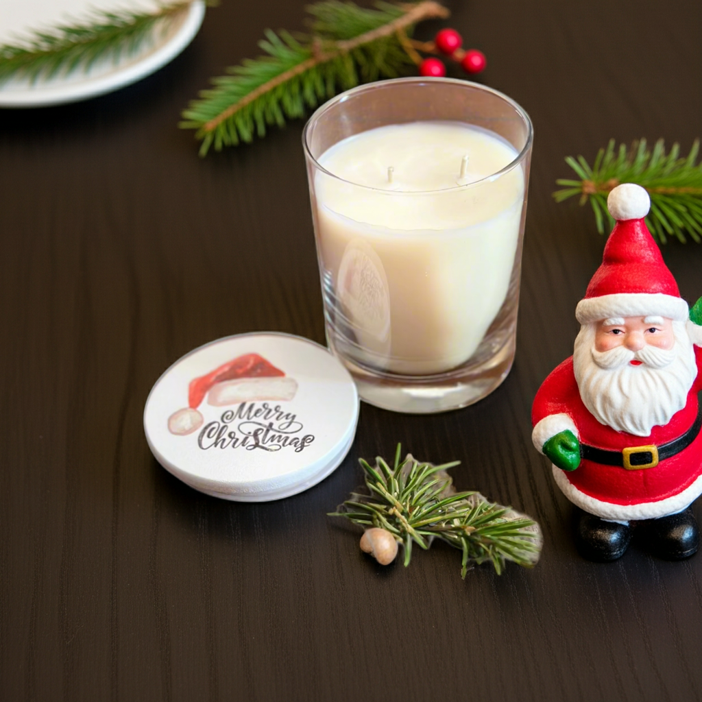 Candle in a glass holder with a Santa Claus figurine and Christmas decorations on a wooden surface.