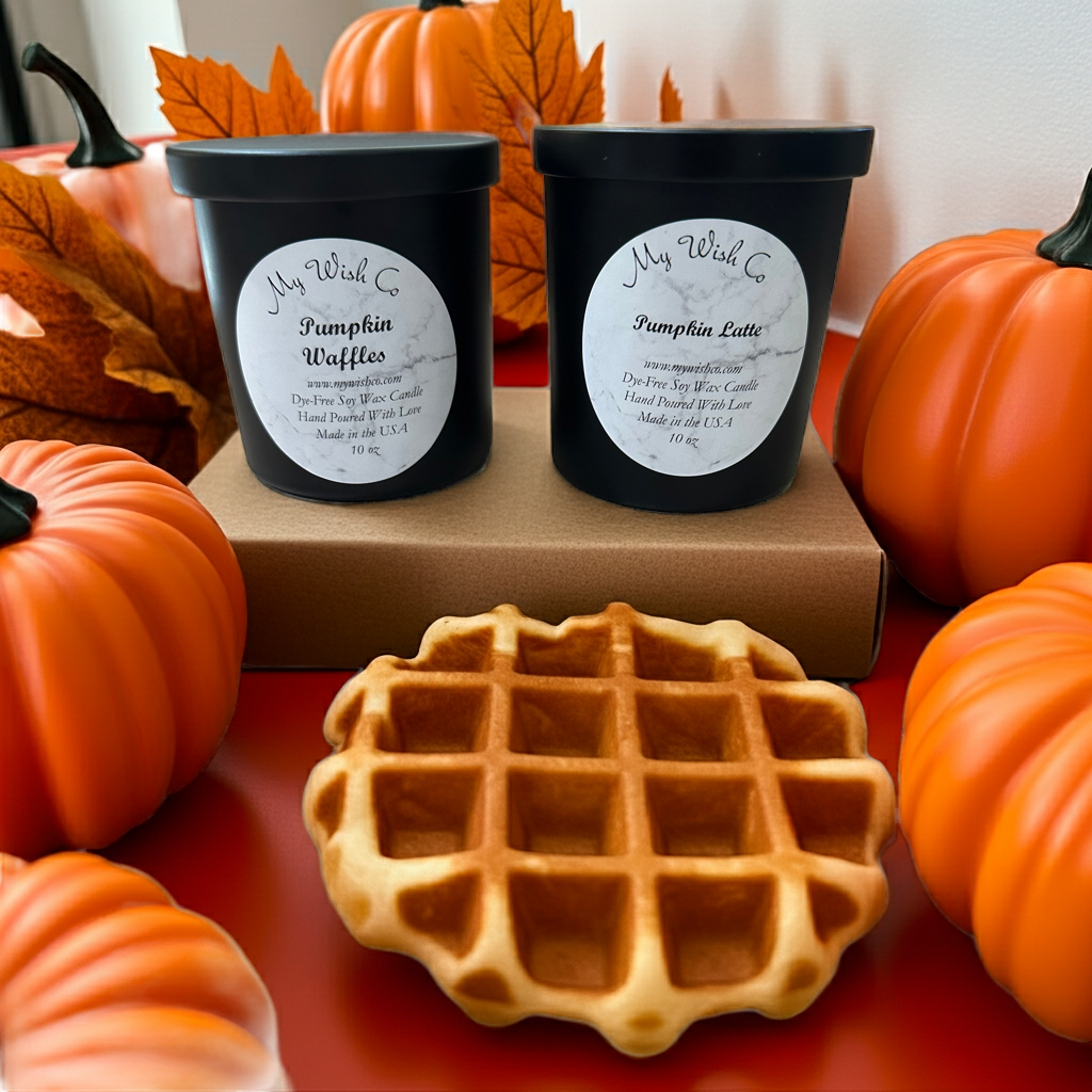 Two black containers labeled 'Pumpkin Waffles' and 'Pumpkin Latte' with a waffle on a table with pumpkins and fall leaves.