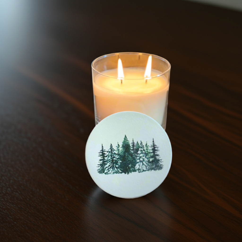 Candle with a forest design coaster on a wooden surface