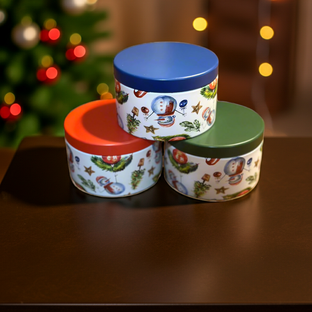 Three decorative tins with colorful lids on a wooden surface, Christmas tree in the background